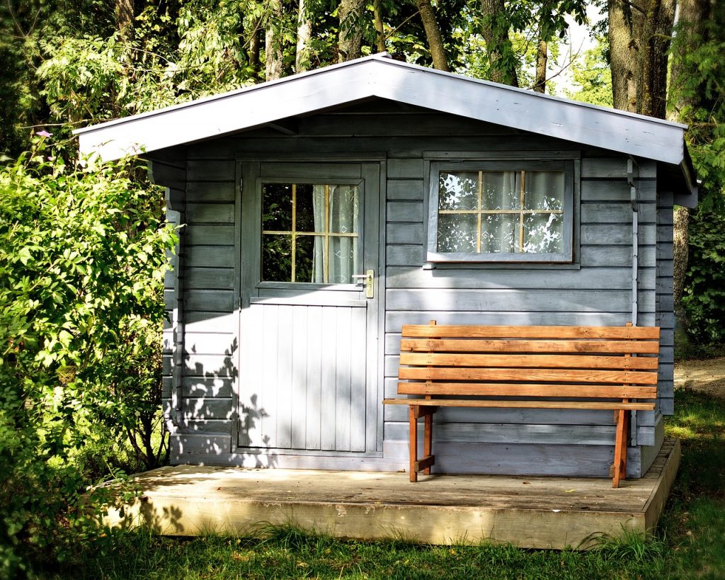 abri de jardin en bois clair avec un banc devant