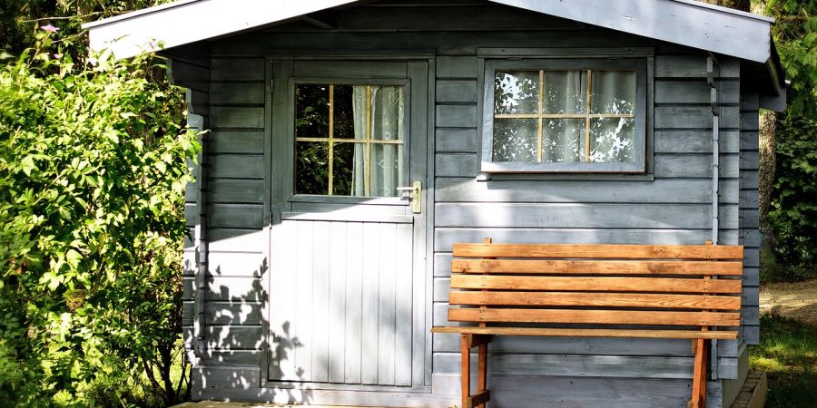 abri de jardin en bois clair avec un banc devant
